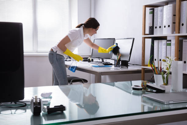 young woman cleaning computer with rag in office